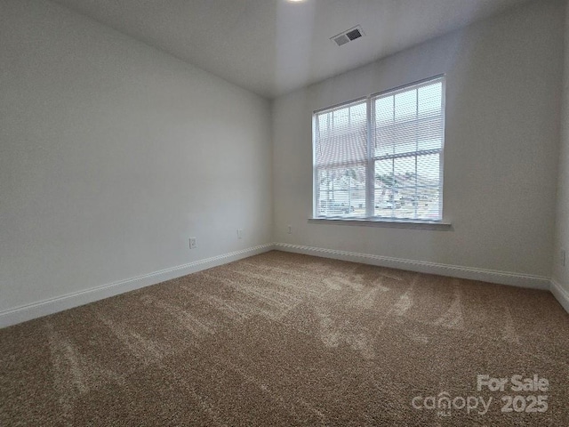 carpeted empty room with visible vents and baseboards
