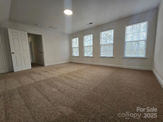 carpeted spare room featuring visible vents and baseboards