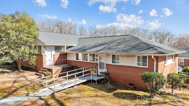 view of front of home with crawl space, brick siding, and roof with shingles