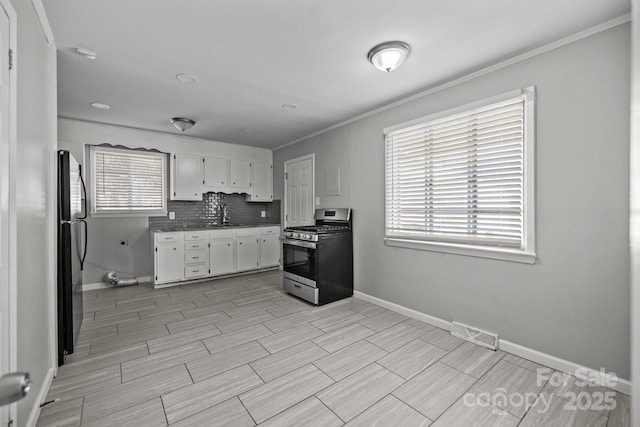 kitchen with stainless steel gas stove, visible vents, white cabinets, freestanding refrigerator, and backsplash