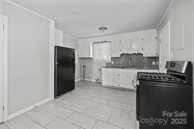 kitchen featuring freestanding refrigerator, white cabinets, a sink, and gas stove