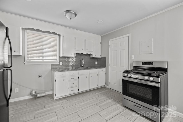 kitchen featuring tasteful backsplash, freestanding refrigerator, stainless steel range with gas cooktop, white cabinetry, and a sink