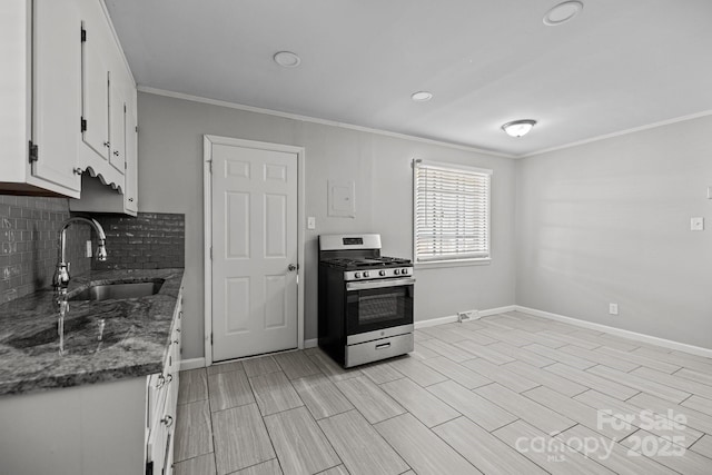 kitchen with a sink, white cabinets, backsplash, gas range, and crown molding