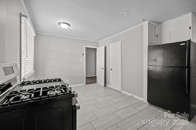 kitchen with range with gas cooktop, baseboards, crown molding, and freestanding refrigerator