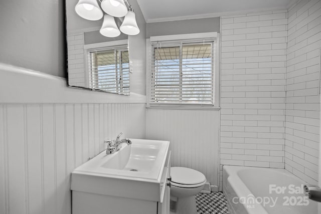 full bathroom with a healthy amount of sunlight, wainscoting, vanity, and toilet