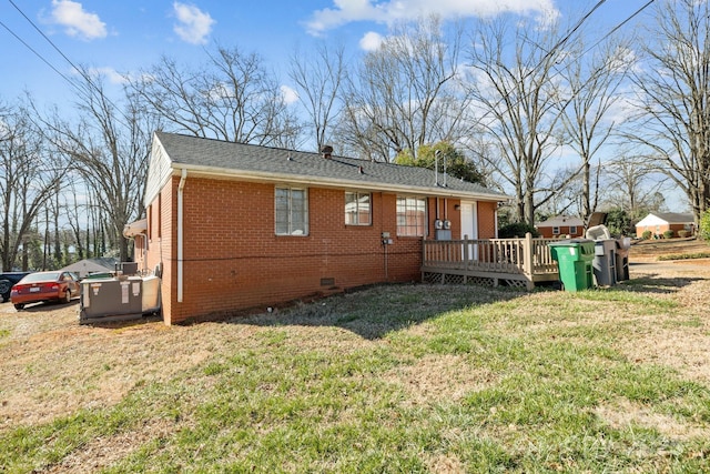 exterior space featuring brick siding, a yard, crawl space, roof with shingles, and a wooden deck