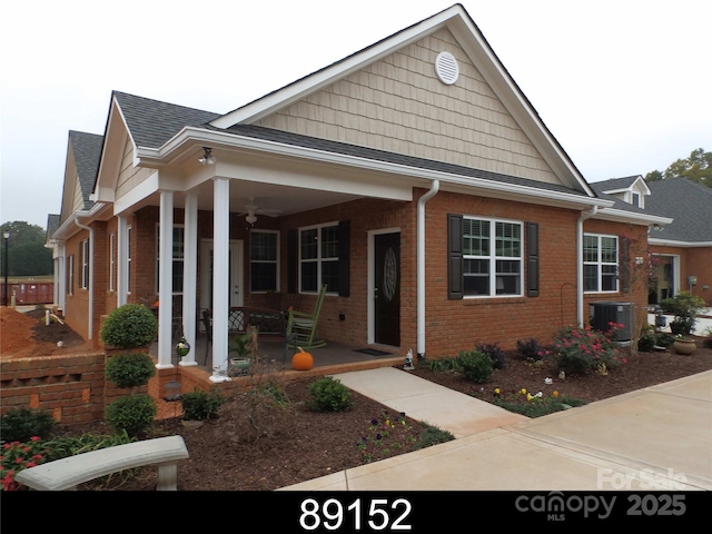 view of front facade with brick siding, ceiling fan, a porch, roof with shingles, and cooling unit