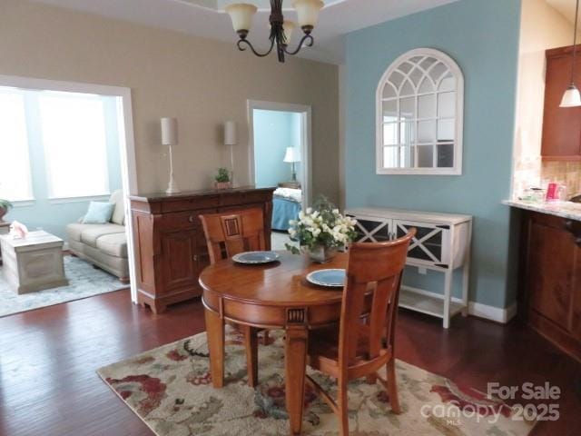 dining space with baseboards, a chandelier, and dark wood-style flooring