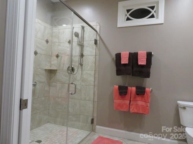 bathroom with a shower stall, toilet, and baseboards