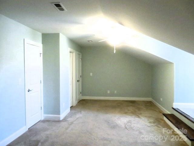 additional living space featuring visible vents, baseboards, and vaulted ceiling