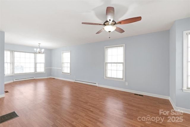 spare room featuring a baseboard heating unit, wood finished floors, visible vents, and a baseboard radiator