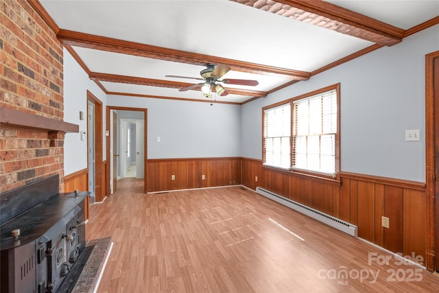 unfurnished living room with a wainscoted wall, beam ceiling, a ceiling fan, light wood-style floors, and baseboard heating