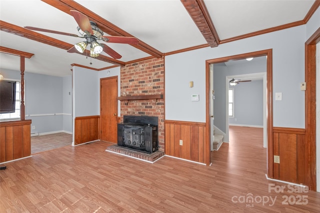 unfurnished living room with wood finished floors, a wainscoted wall, and a healthy amount of sunlight