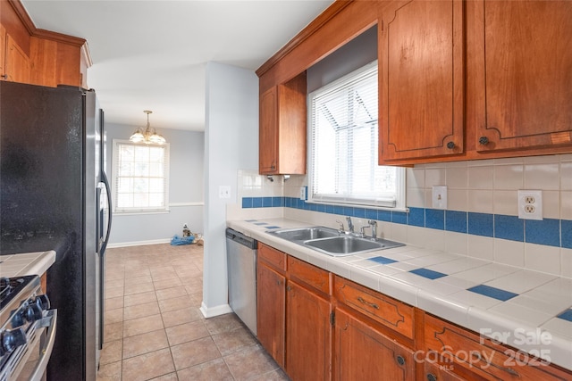 kitchen with brown cabinets, a sink, tasteful backsplash, stainless steel appliances, and light tile patterned floors