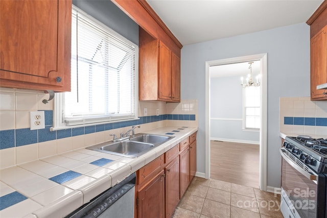 kitchen with tile countertops, light tile patterned floors, decorative backsplash, stainless steel appliances, and a sink