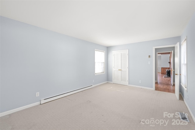 carpeted empty room featuring baseboard heating, visible vents, and baseboards