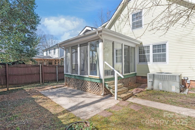 view of side of home featuring entry steps, a sunroom, central AC, and fence