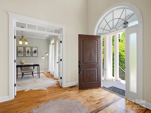 entryway featuring an inviting chandelier, baseboards, a high ceiling, and wood finished floors