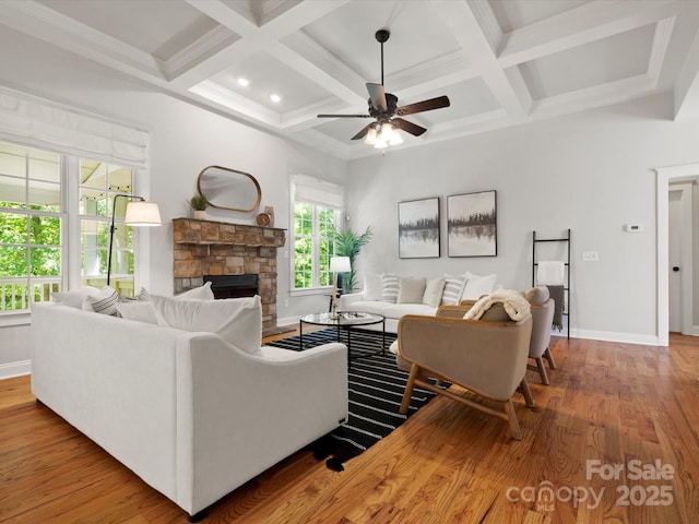 living area featuring a ceiling fan, a fireplace, wood finished floors, baseboards, and coffered ceiling