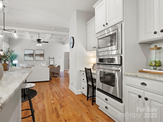 kitchen with white cabinets, ceiling fan, appliances with stainless steel finishes, light wood-style floors, and coffered ceiling