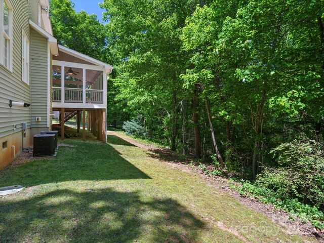 view of yard featuring a sunroom, ceiling fan, cooling unit, and stairway