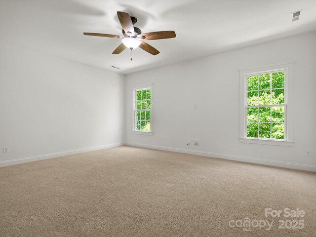 empty room with baseboards, light carpet, a ceiling fan, and visible vents