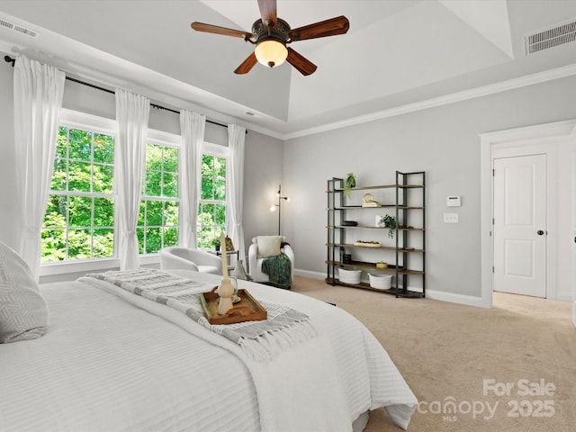 carpeted bedroom with visible vents, a raised ceiling, baseboards, and crown molding