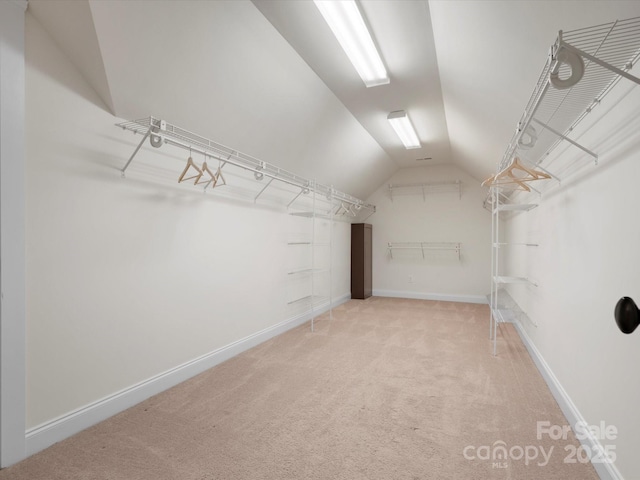 spacious closet with light carpet and vaulted ceiling