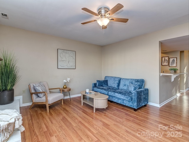 living room with light wood-style floors, ceiling fan, visible vents, and baseboards