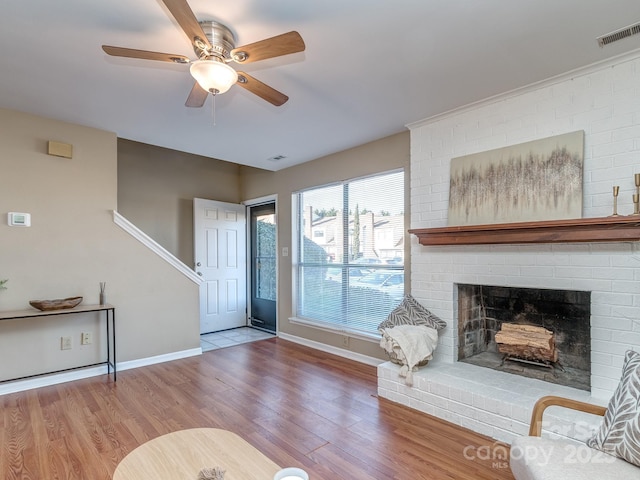 living area featuring visible vents, a fireplace, baseboards, and wood finished floors