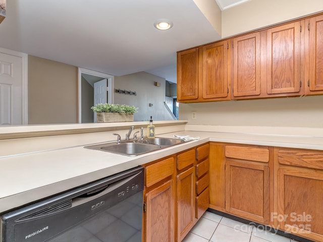 kitchen featuring brown cabinets, light countertops, light tile patterned flooring, a sink, and dishwasher