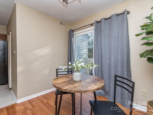 dining area featuring light wood-type flooring, visible vents, and baseboards