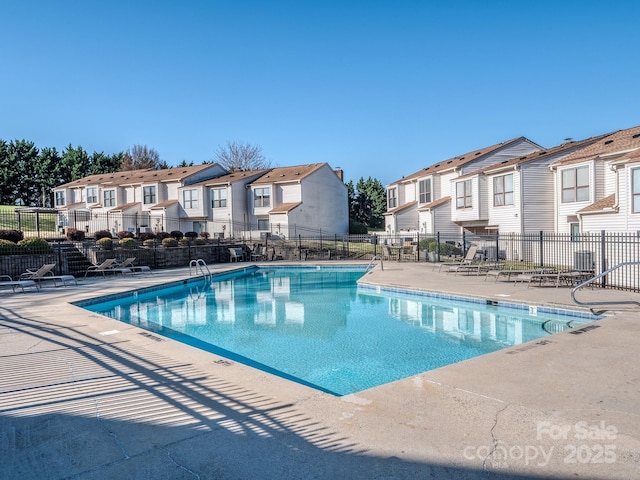 community pool featuring a patio, fence, and a residential view