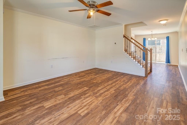 spare room with ceiling fan with notable chandelier, wood finished floors, baseboards, stairs, and crown molding