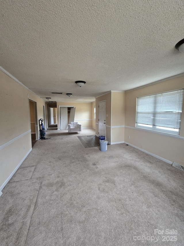 unfurnished living room with visible vents, baseboards, carpet, and a textured ceiling