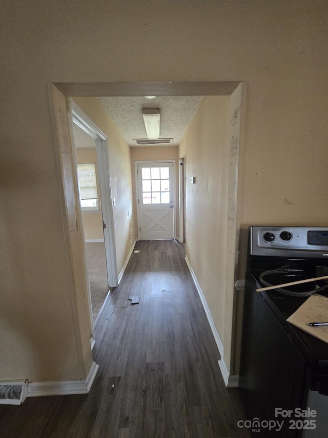 doorway featuring visible vents, a textured ceiling, baseboards, and dark wood-style flooring