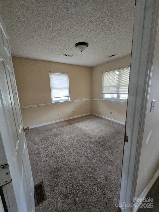 unfurnished bedroom featuring visible vents, a textured ceiling, baseboards, and carpet floors