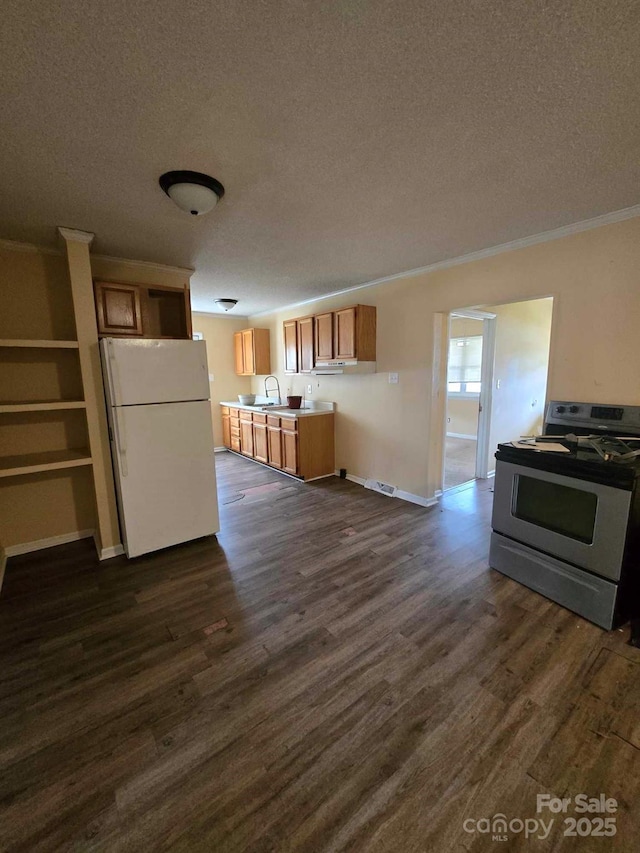 kitchen with dark wood-style flooring, stainless steel gas stove, freestanding refrigerator, and a sink