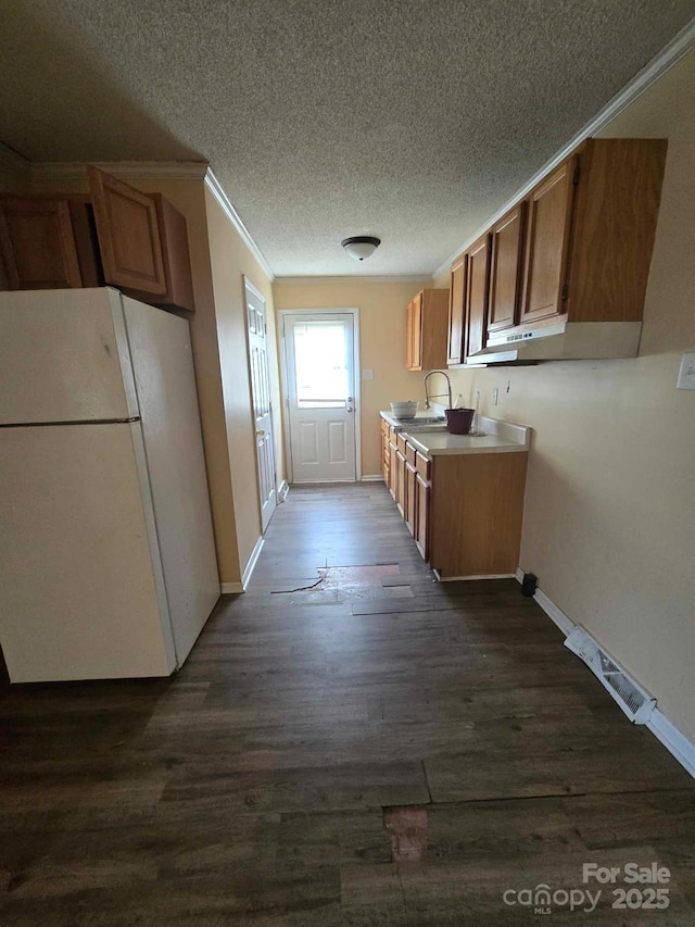 kitchen featuring a sink, brown cabinets, dark wood-style floors, and freestanding refrigerator