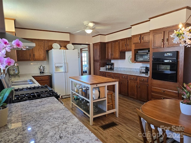 kitchen with visible vents, crown molding, black appliances, and wood finished floors