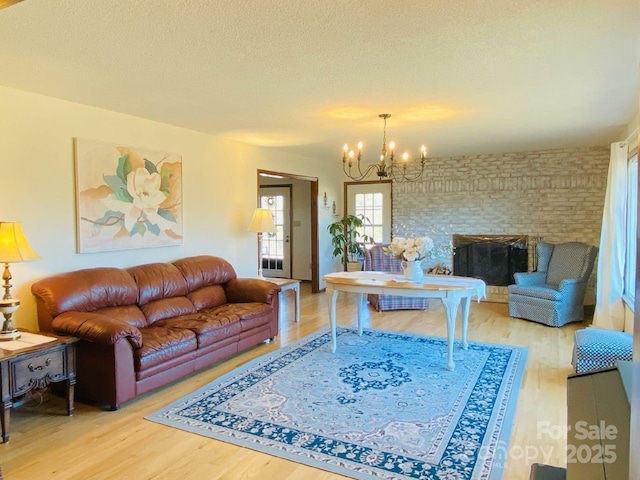 living room with a chandelier, a textured ceiling, a fireplace, and wood finished floors