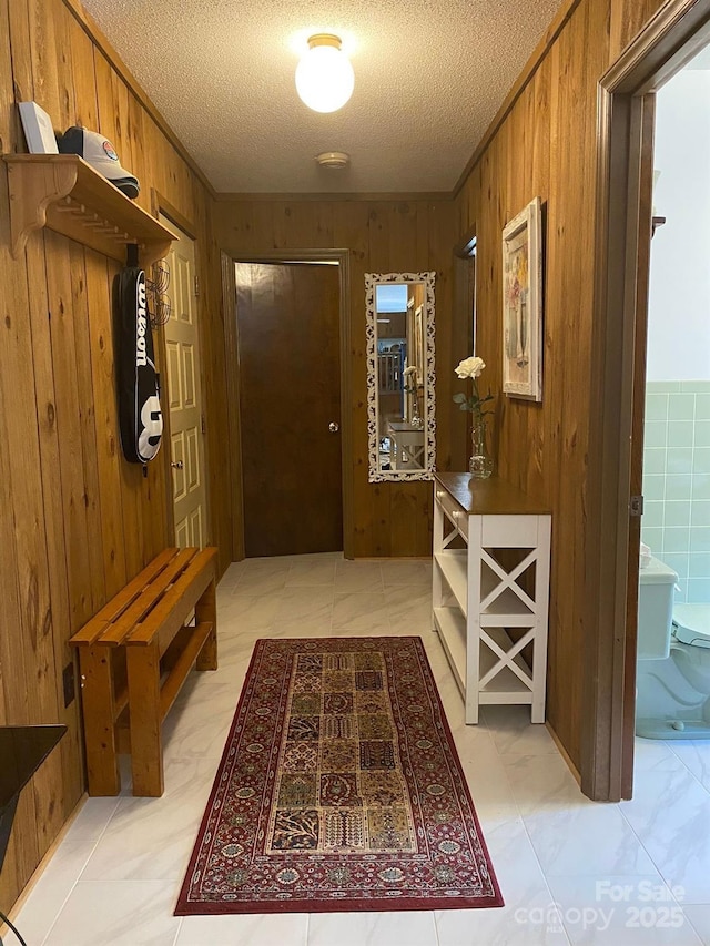 interior space featuring wooden walls, ornamental molding, and a textured ceiling