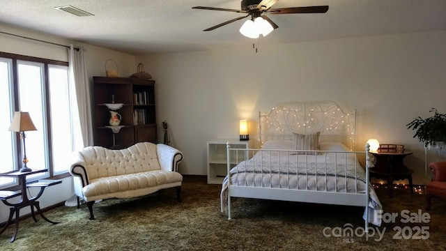 bedroom with visible vents, a textured ceiling, carpet flooring, and multiple windows