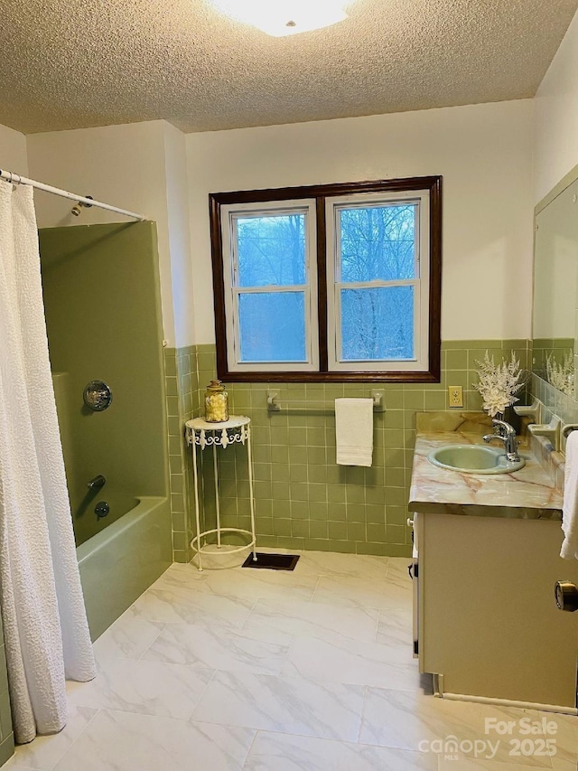 bathroom featuring marble finish floor, shower / bathtub combination with curtain, a textured ceiling, and vanity