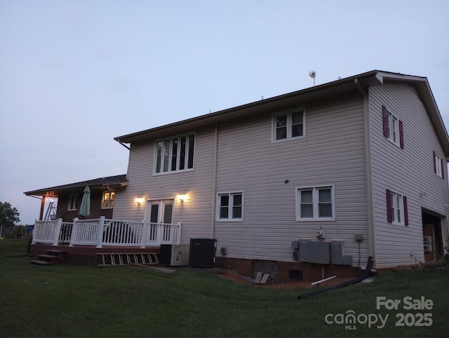 back of property with a lawn, a wooden deck, and central air condition unit