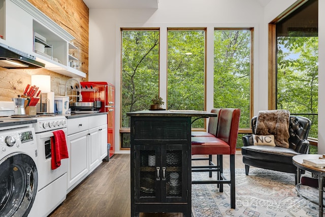 kitchen with hardwood / wood-style floors, white range with gas cooktop, washer / dryer, white cabinetry, and backsplash