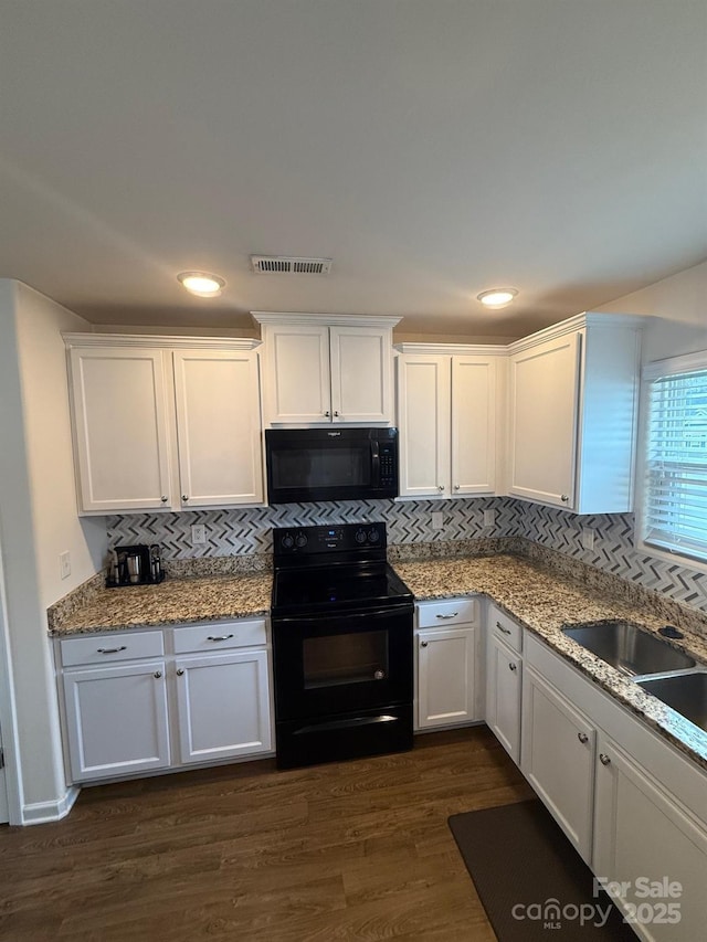 kitchen with black appliances, dark wood finished floors, visible vents, and white cabinetry