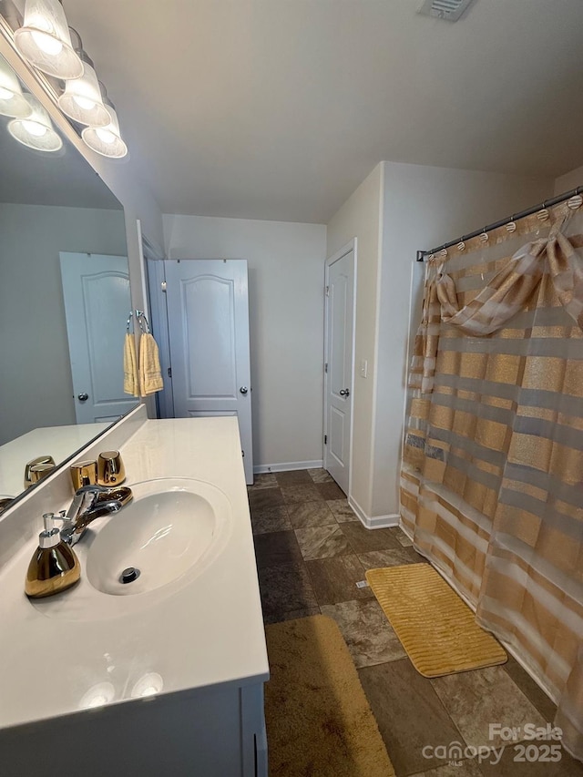 full bath featuring a shower with shower curtain, vanity, and baseboards