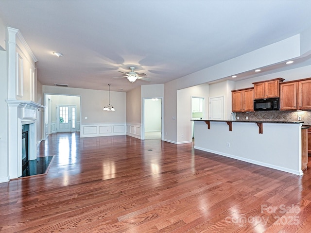 unfurnished living room with dark wood-style floors, a ceiling fan, visible vents, a high end fireplace, and a decorative wall