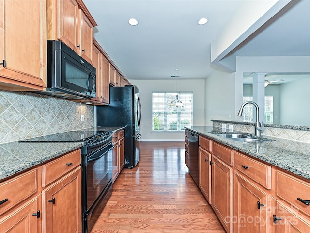 kitchen with black appliances, a sink, tasteful backsplash, light wood finished floors, and decorative columns